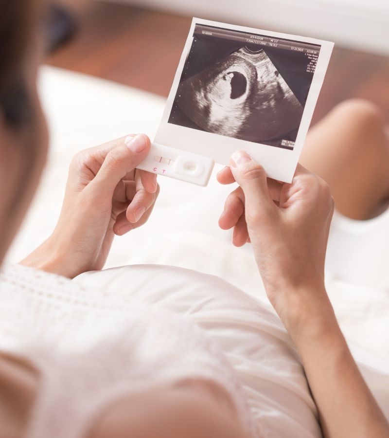 Pregnant woman smiling at her sonogram photo after a successful personalized fertility program