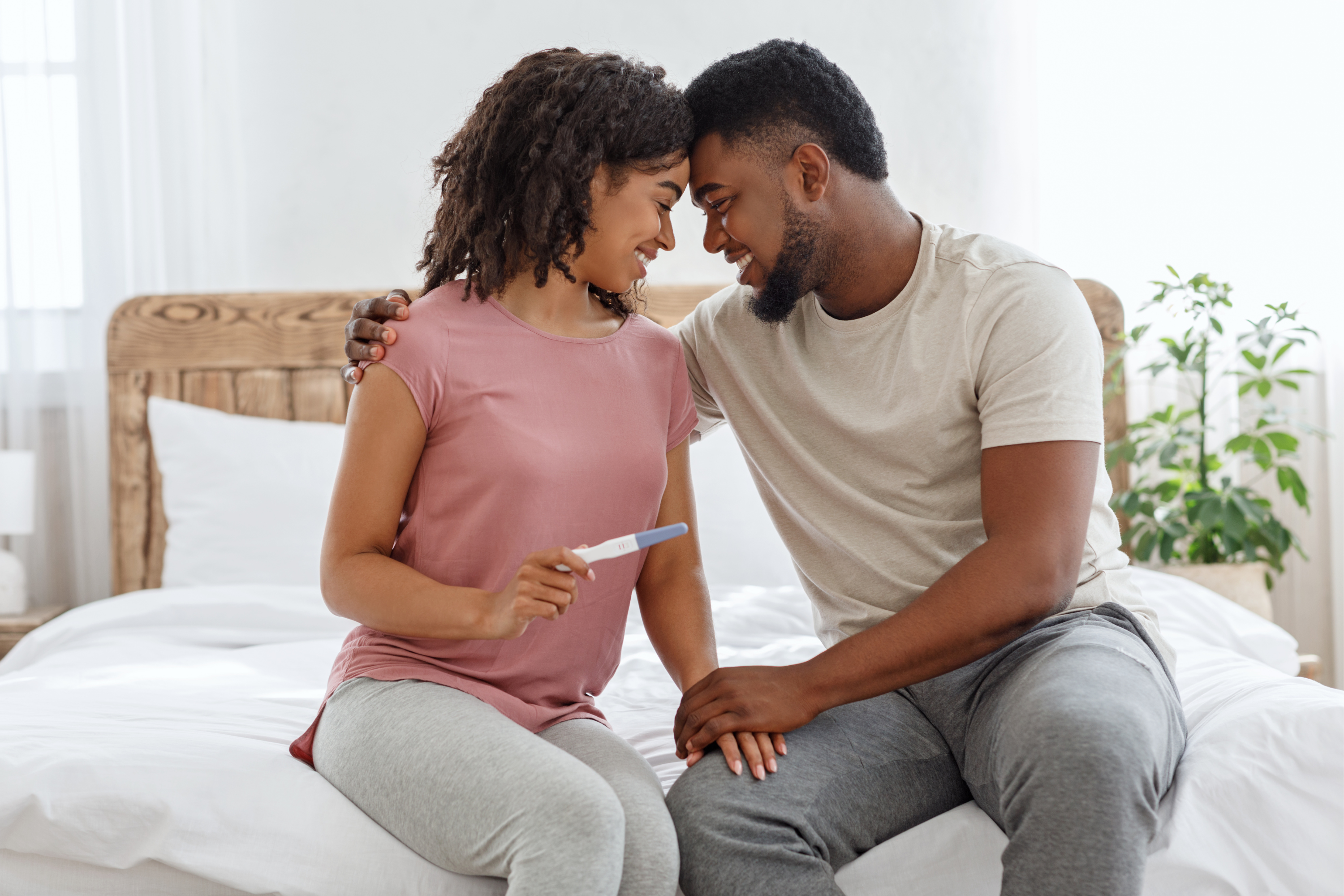 Happy couple holding a positive pregnancy test after completing a personalized fertility program