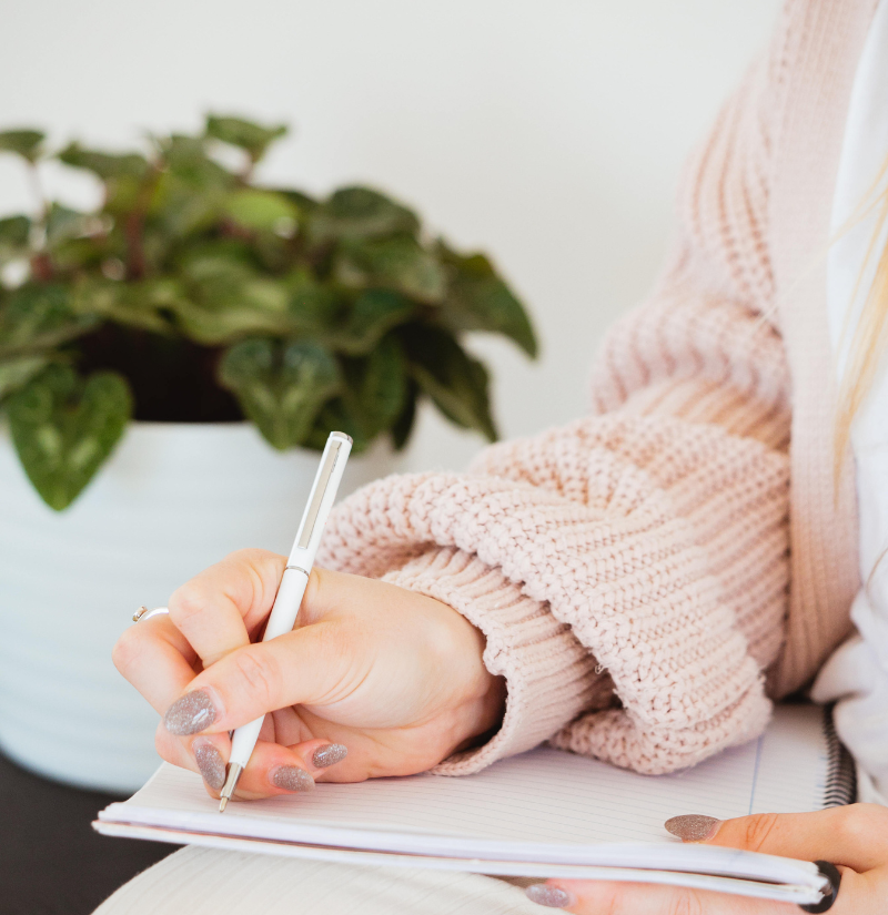 Woman writing notes in her notebook during a personalized fertility and women’s health consultation