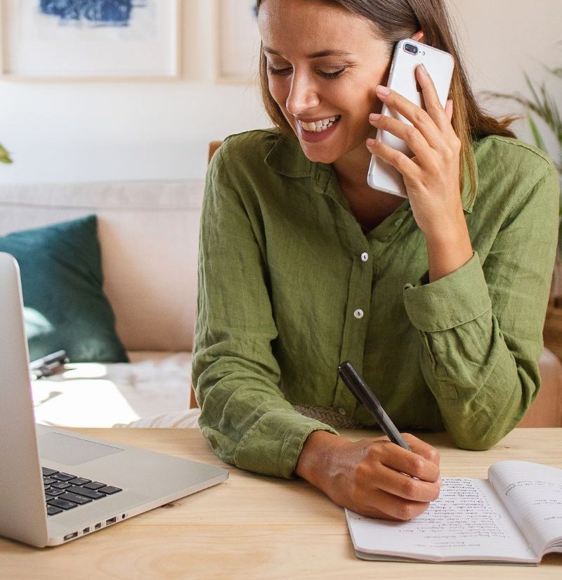 Smiling woman on her phone taking notes during a personalized fertility and women's health consultation with Dr. Kathy Xydis