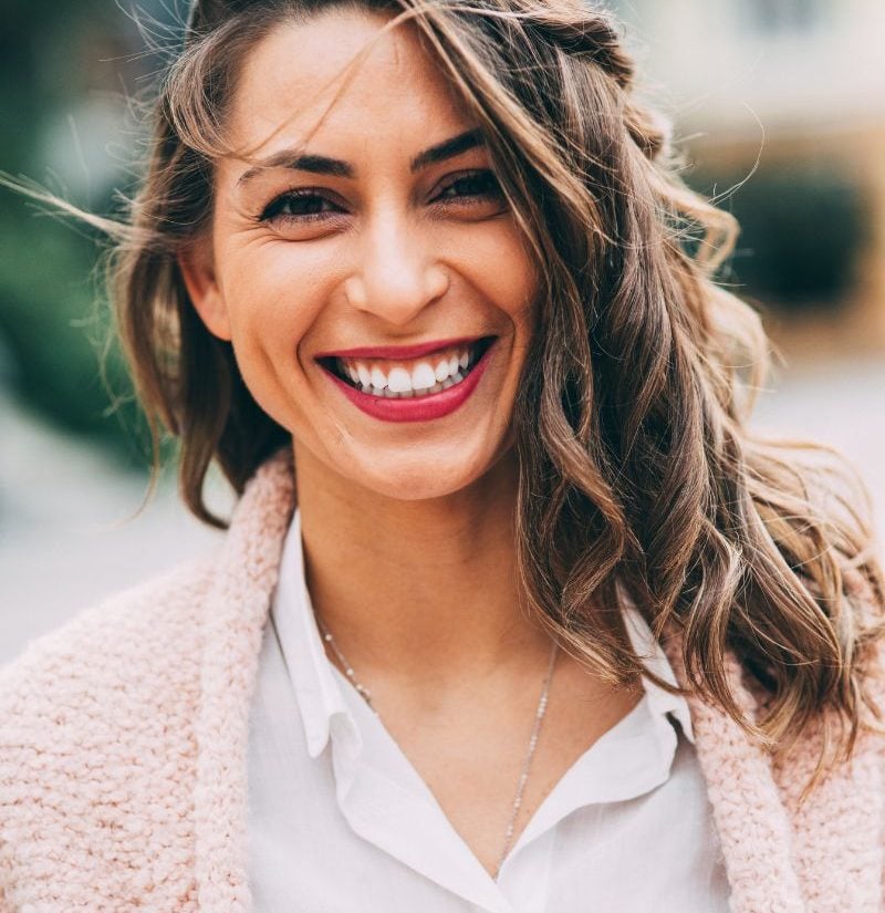 Smiling woman outdoors after achieving optimal health through personalized fertility and nutrition care